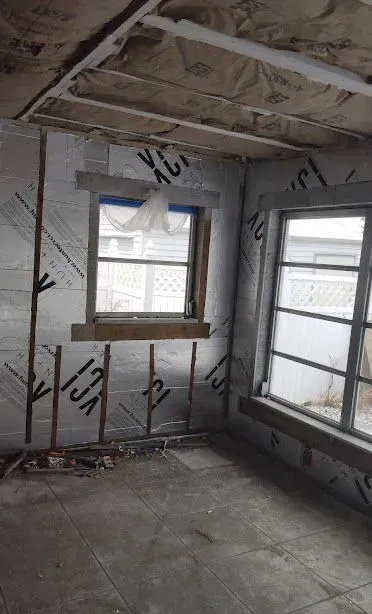 Partially finished room with exposed insulation, two windows, and bare concrete floor