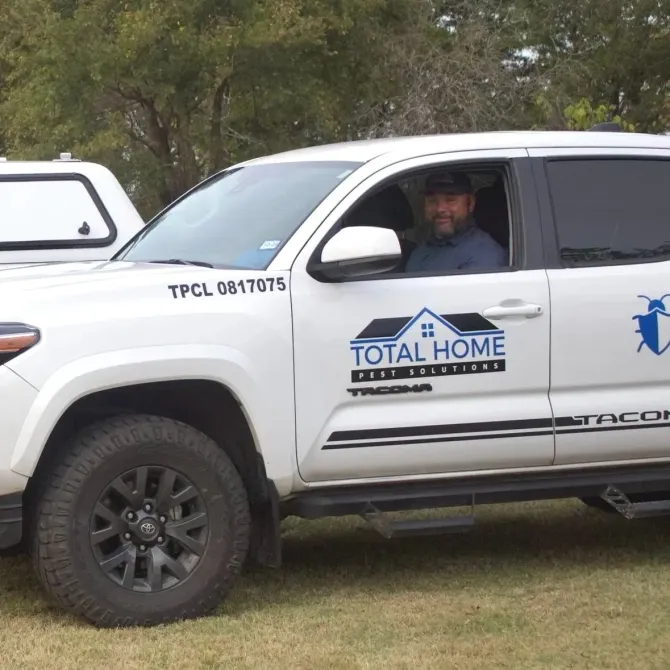 White Total Home Pest Solutions truck with a driver.