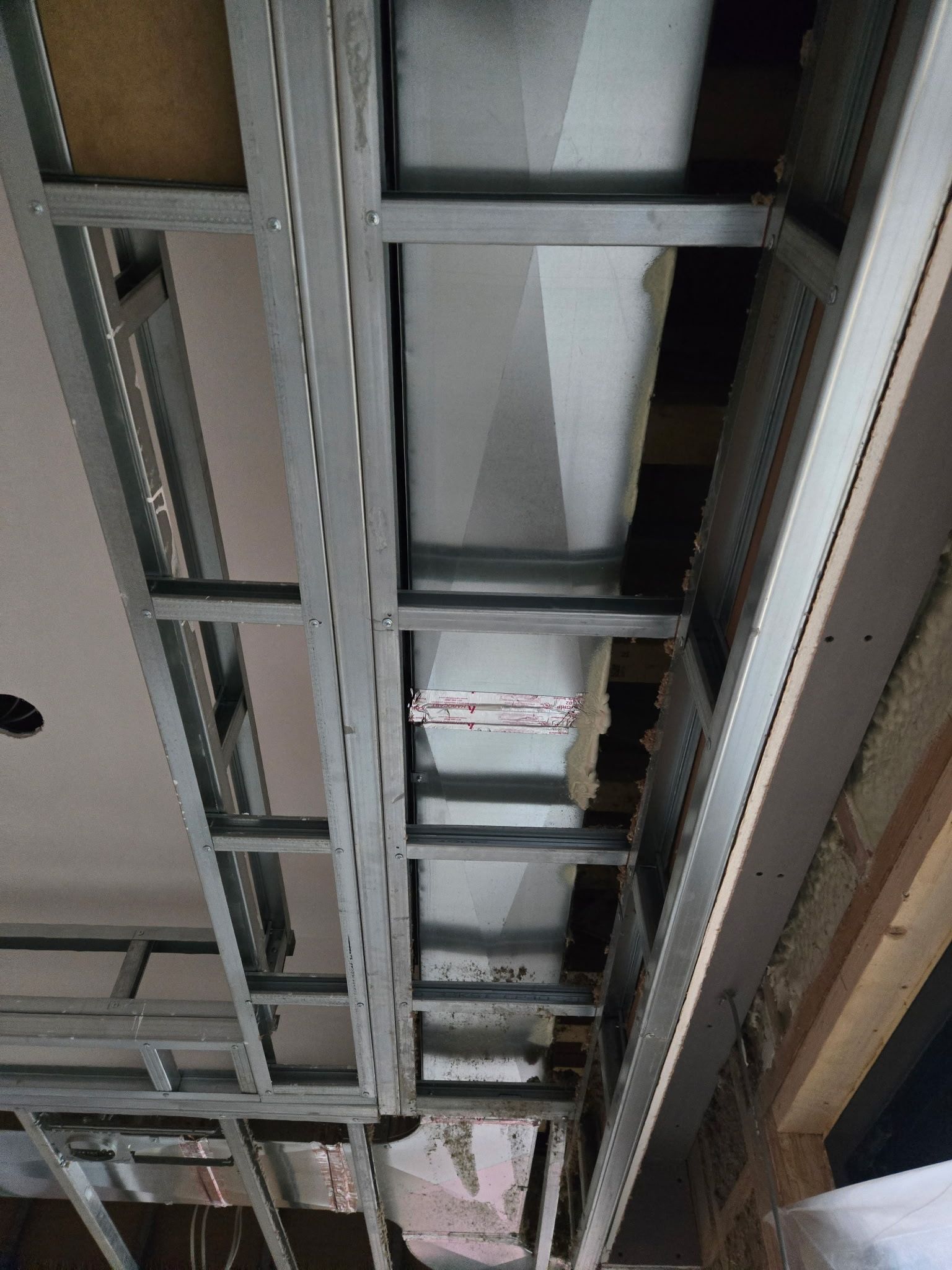 Ceiling view of exposed metal framing and ductwork in a building under construction