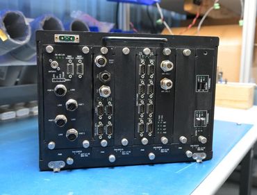 Black electronic component with various ports and connectors on a blue surface