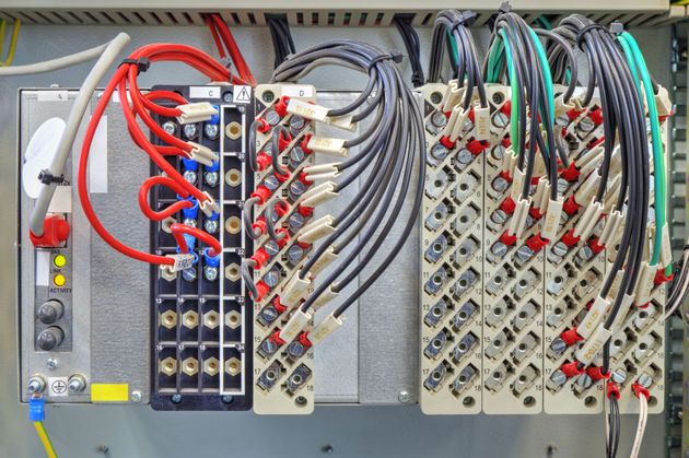 Electrical control panel with dense red, blue, gray, and black wiring connected to terminal blocks
