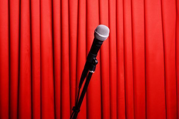 Microphone on stand against a red stage curtain.