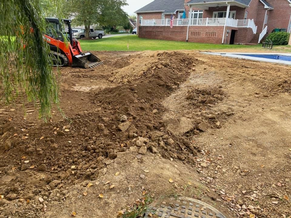 A small orange construction vehicle excavates dirt in a residential yard, near a pool and a house.