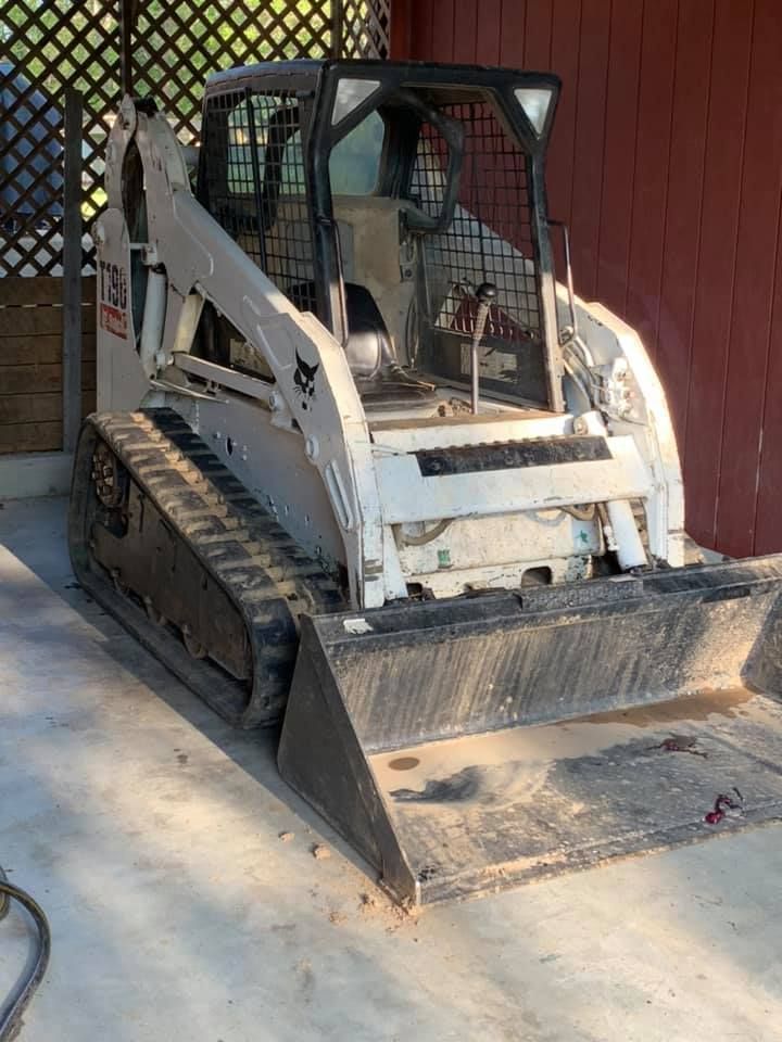 White Bobcat T190 compact track loader parked on concrete, facing forward. The machine is under a wooden structure.