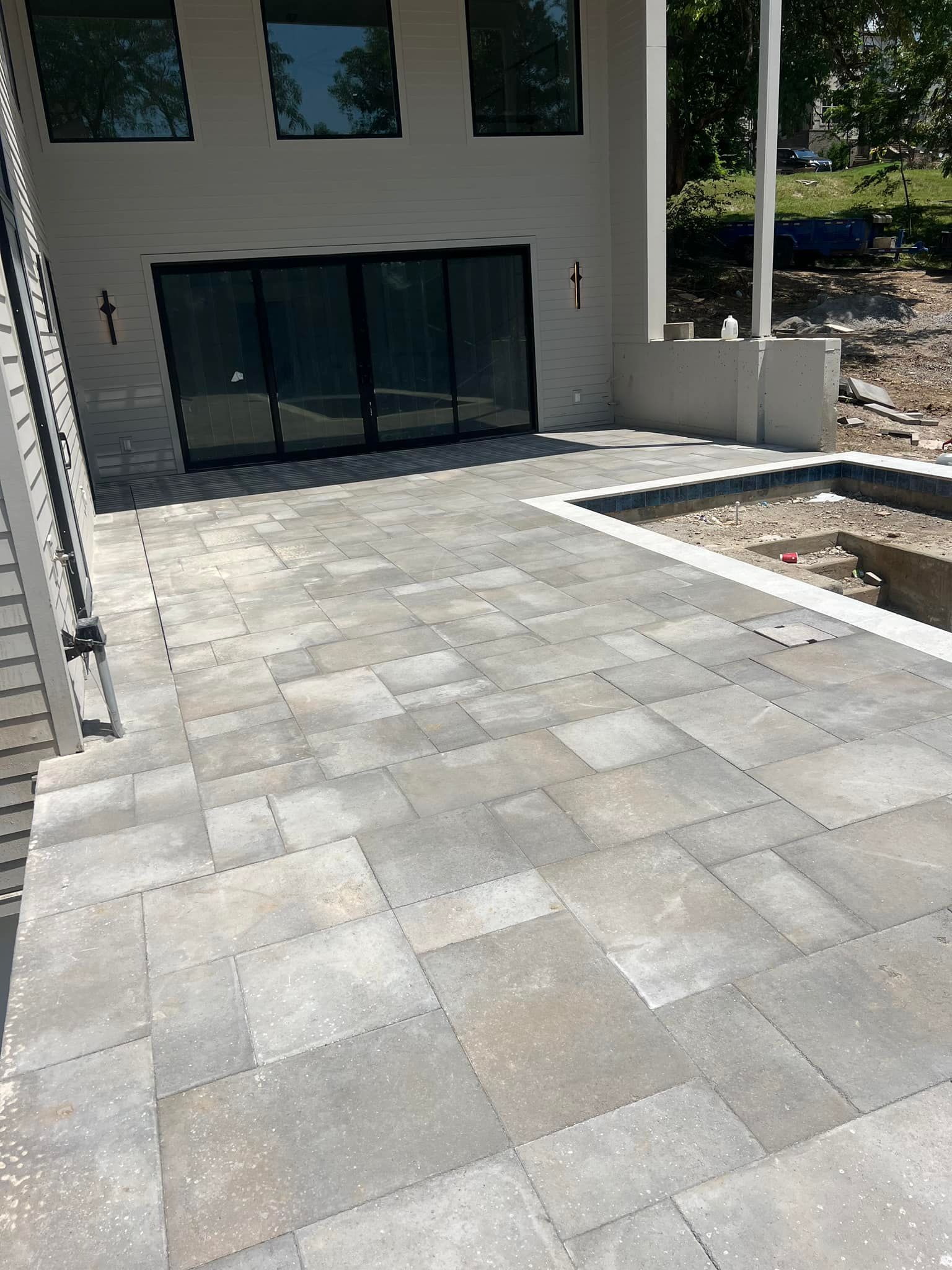 Stone patio with sliding glass doors, steps, and a partially built pool.