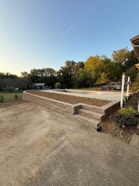 A newly constructed backyard pool with tiered retaining walls and steps.