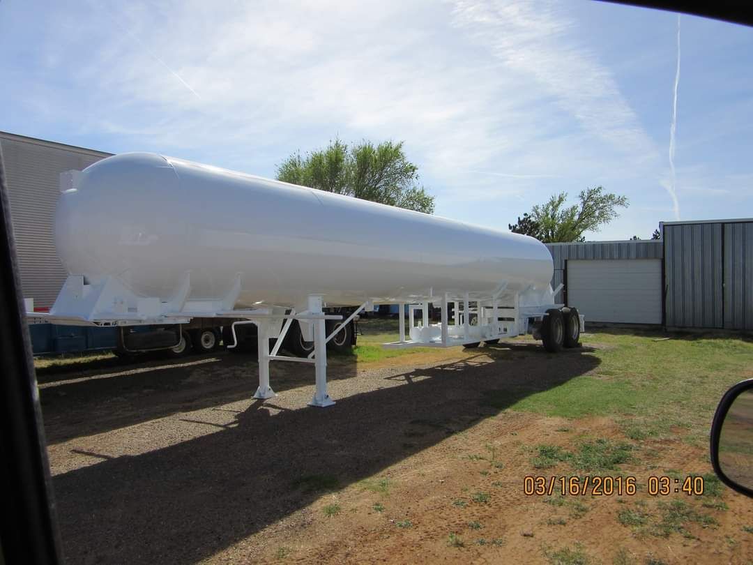 A large white tank is parked in a grassy field.