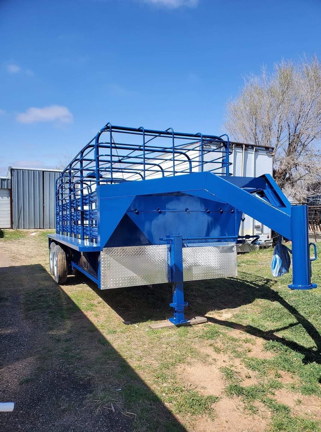 A blue trailer is parked in a grassy field.