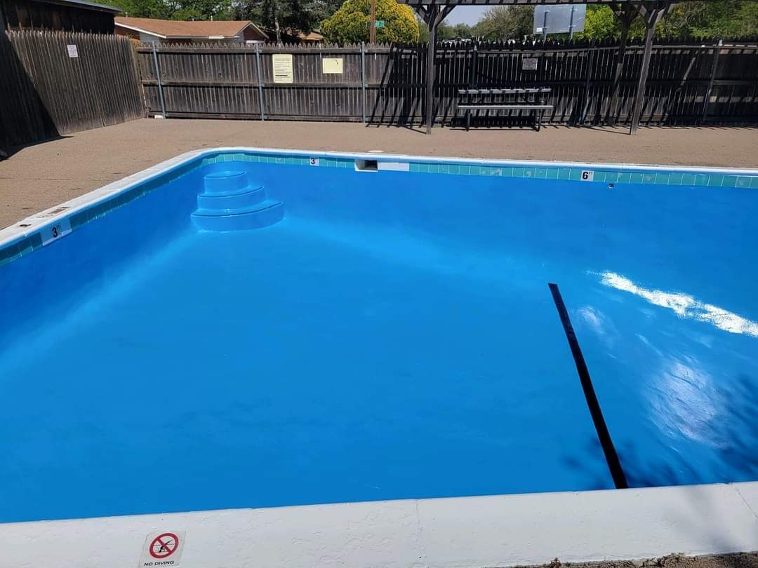 A large blue swimming pool with a fence in the background.