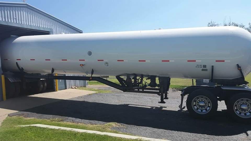 A large white tanker trailer is parked in front of a building.