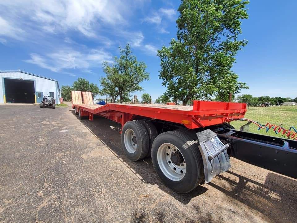 A red trailer is parked on the side of the road in front of a building.