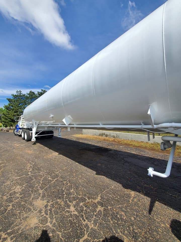 A large white pipe is sitting on the side of a road.