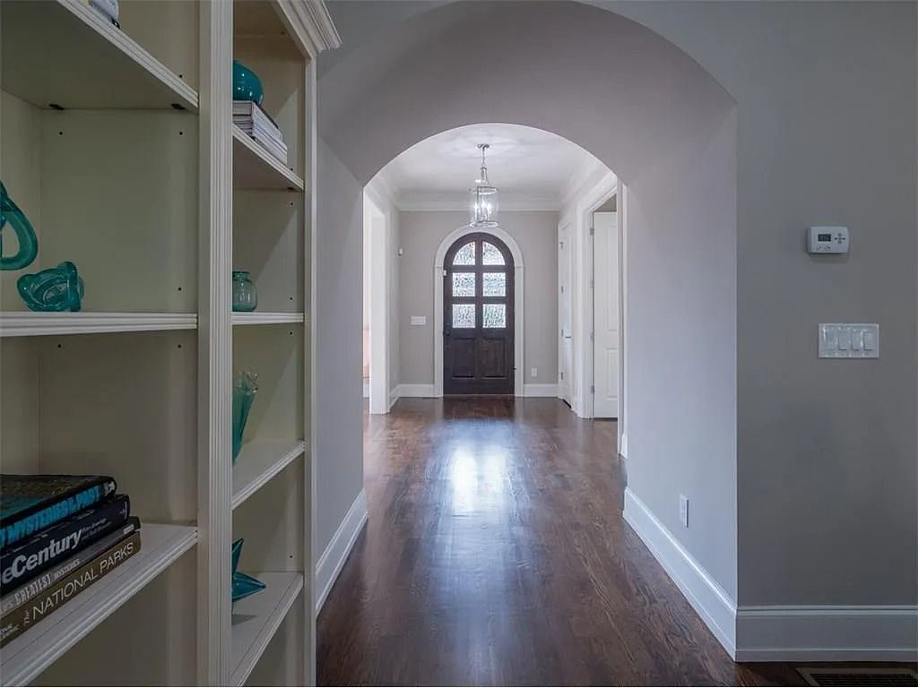 A hallway in a house with a door and shelves.