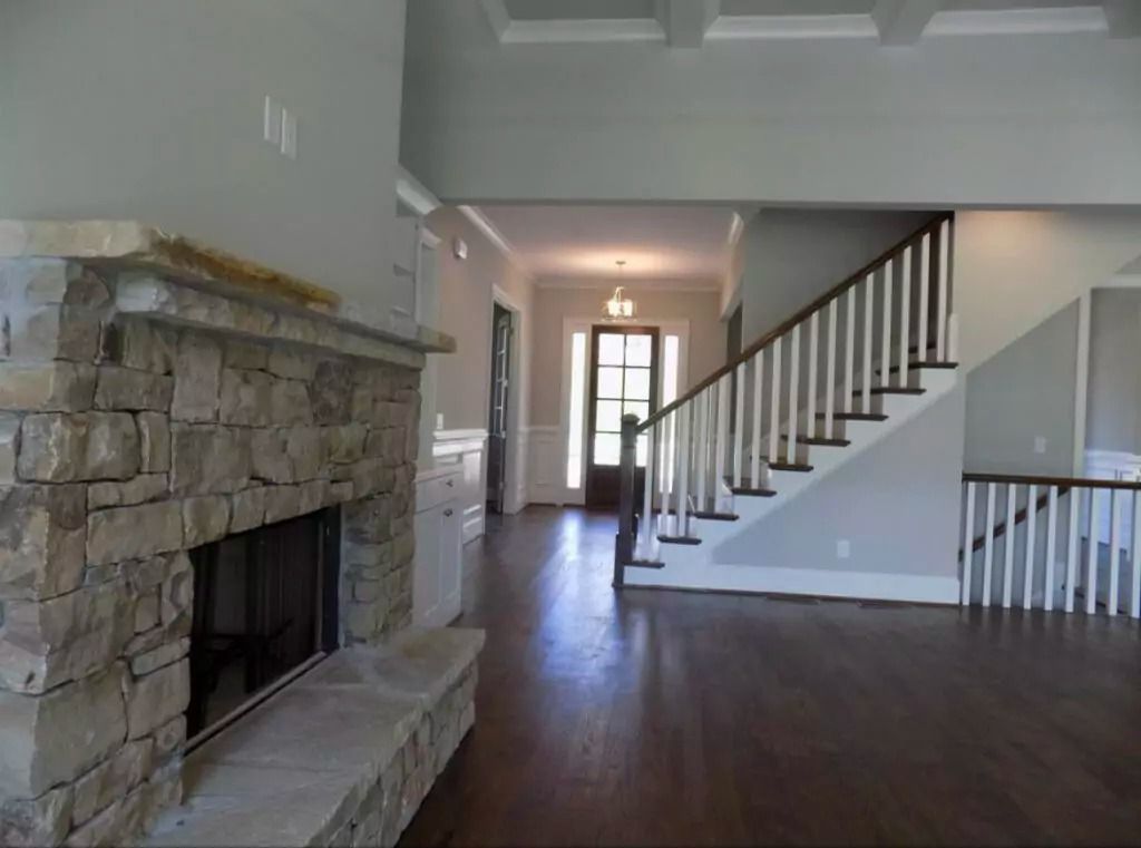 An empty house with a stone fireplace and stairs