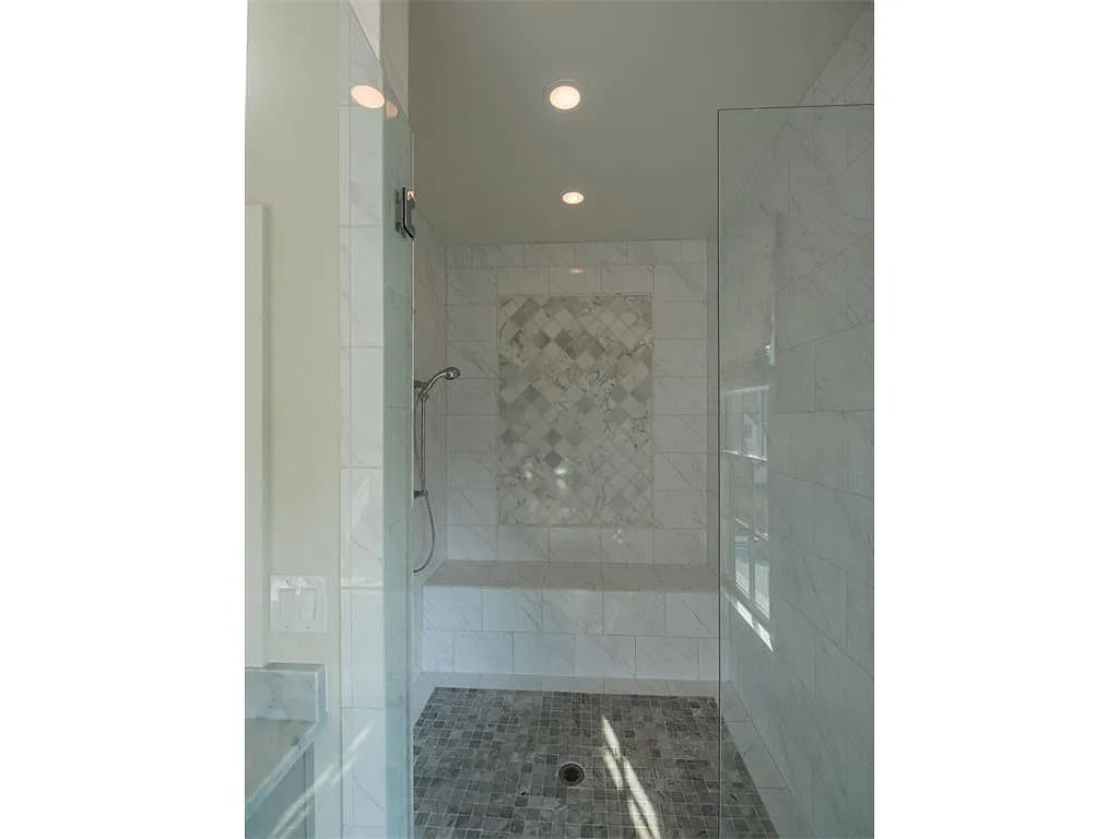 A bathroom with a walk in shower and a bench.