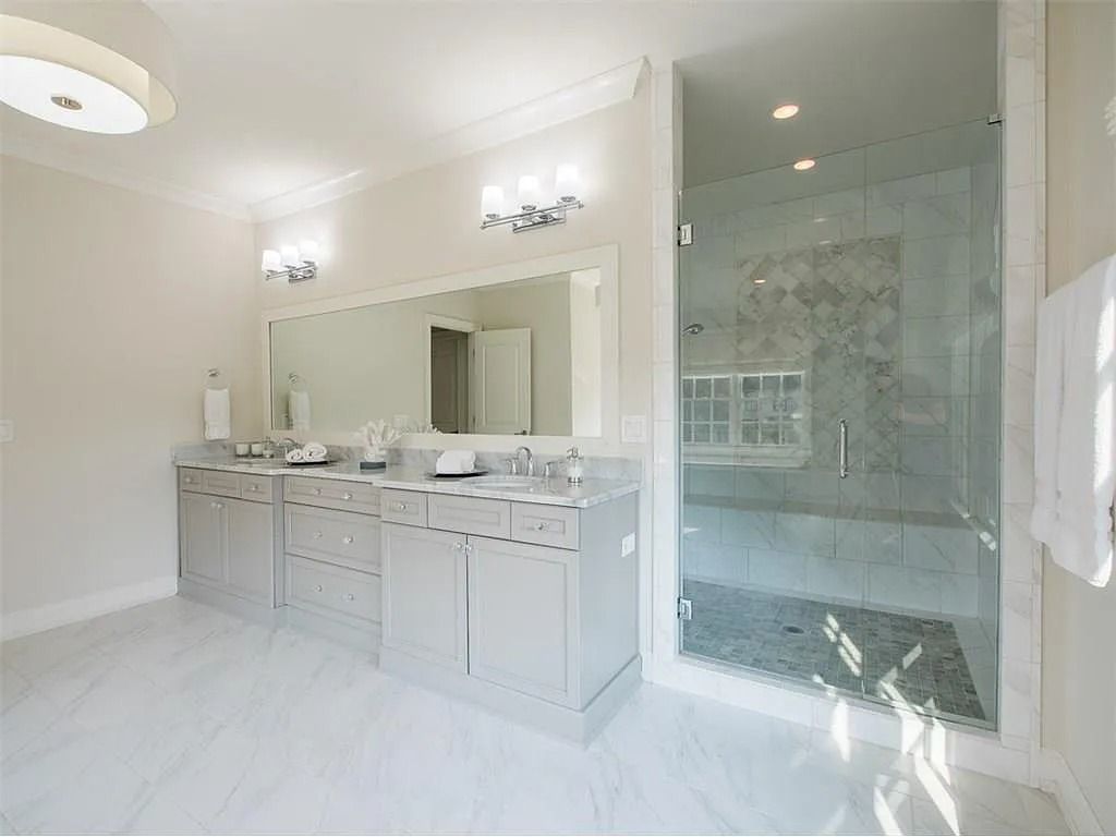 A bathroom with two sinks and a walk in shower.