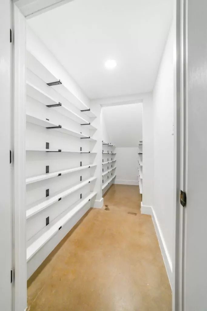 A walk in closet with lots of shelves and a wooden floor.