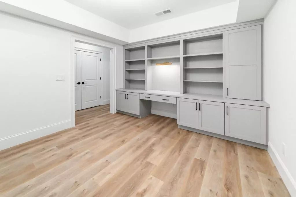 An empty room with a desk and shelves in it.