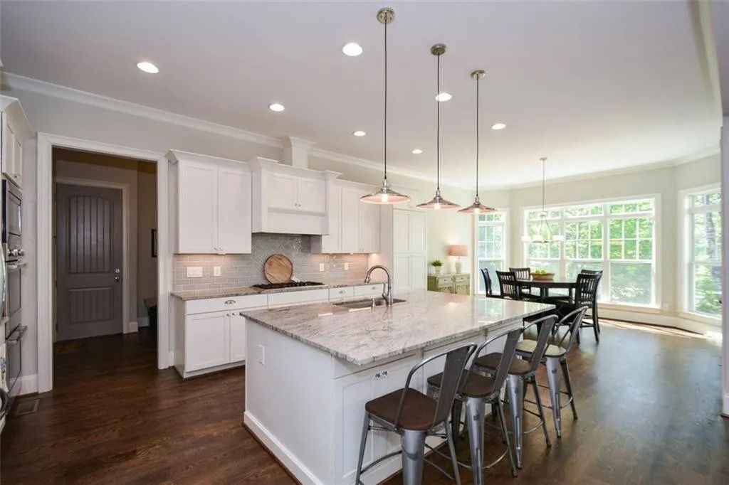 A kitchen with white cabinets and granite counter tops and a large island.