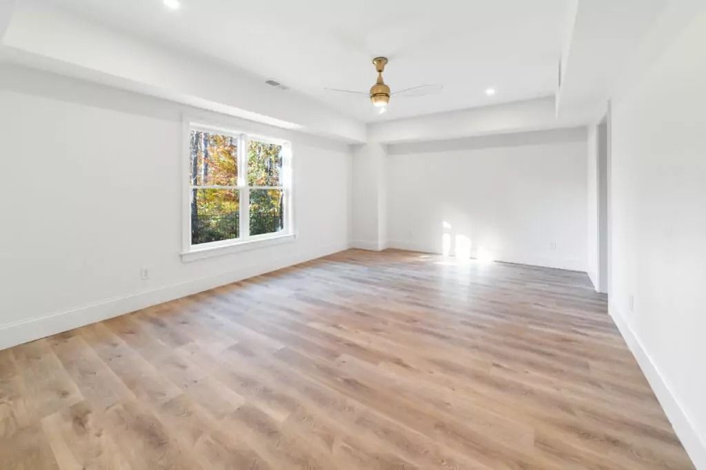 An empty living room with hardwood floors and a ceiling fan.