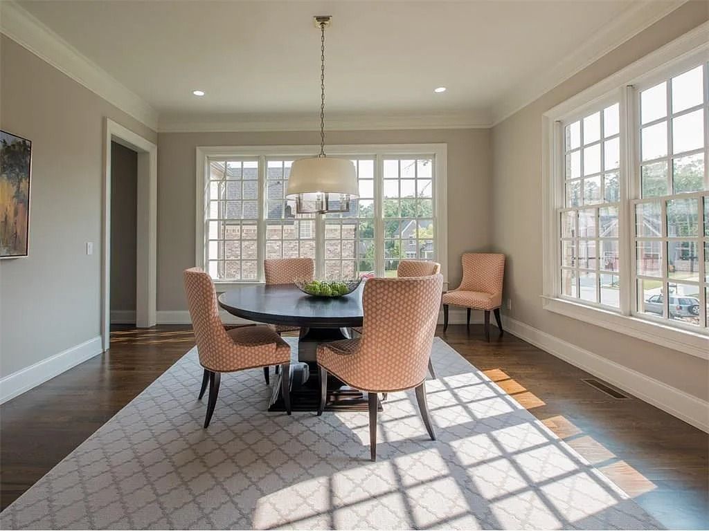 A dining room with a table and chairs and lots of windows.