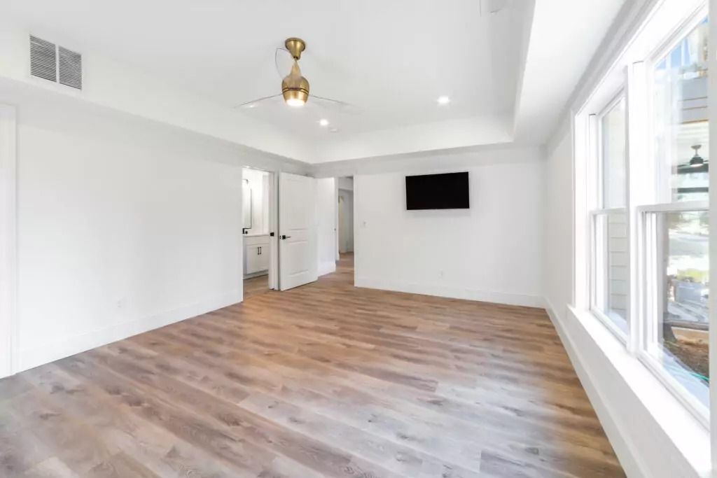 An empty living room with hardwood floors and a ceiling fan