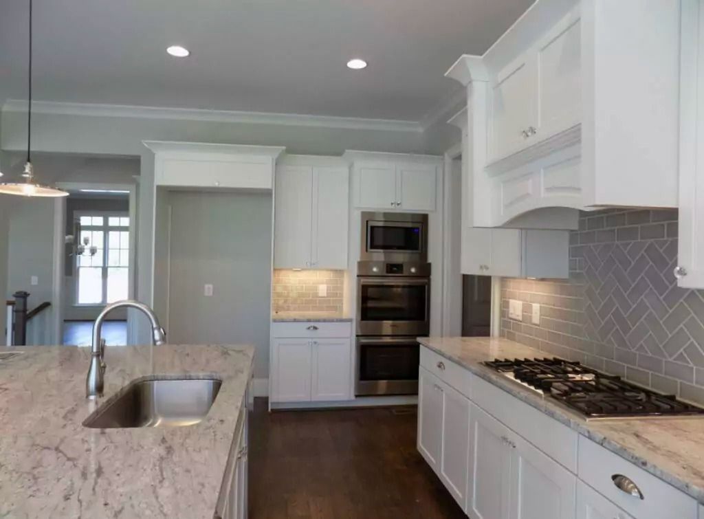 A kitchen with white cabinets and granite counter tops.