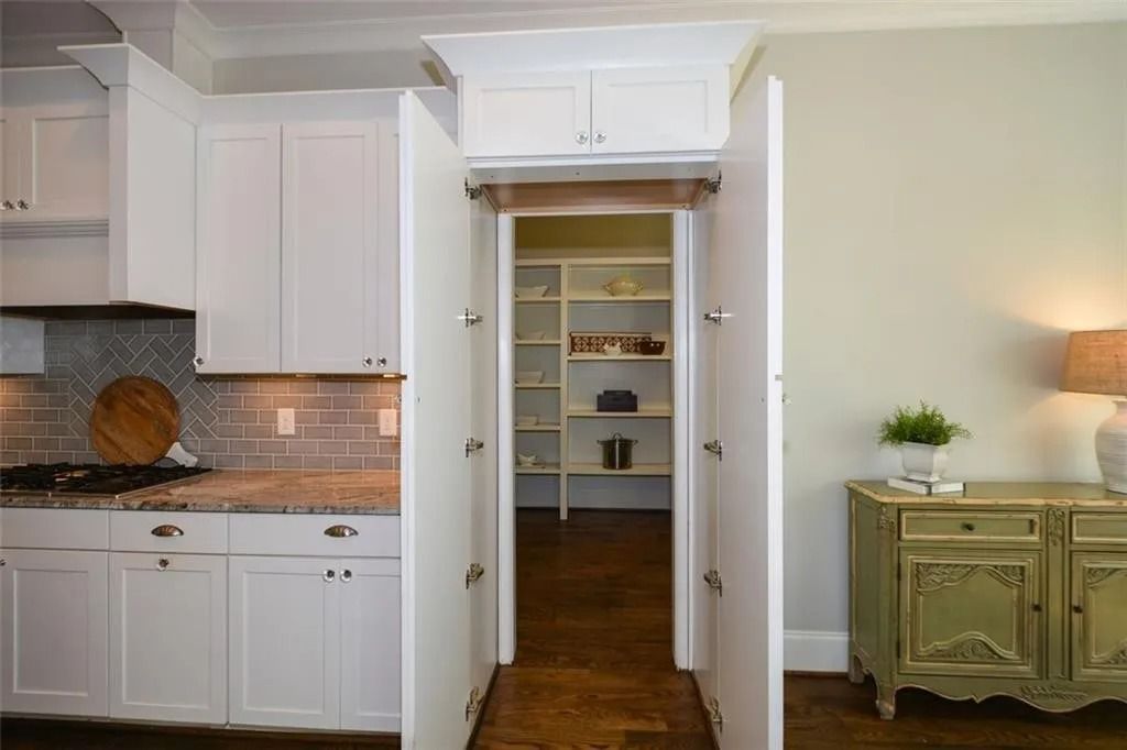 A kitchen with white cabinets and a walk in pantry