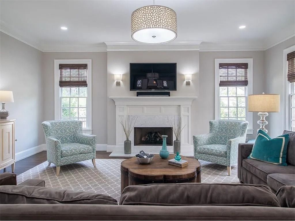 A living room with a couch , chairs , a fireplace and a flat screen tv.