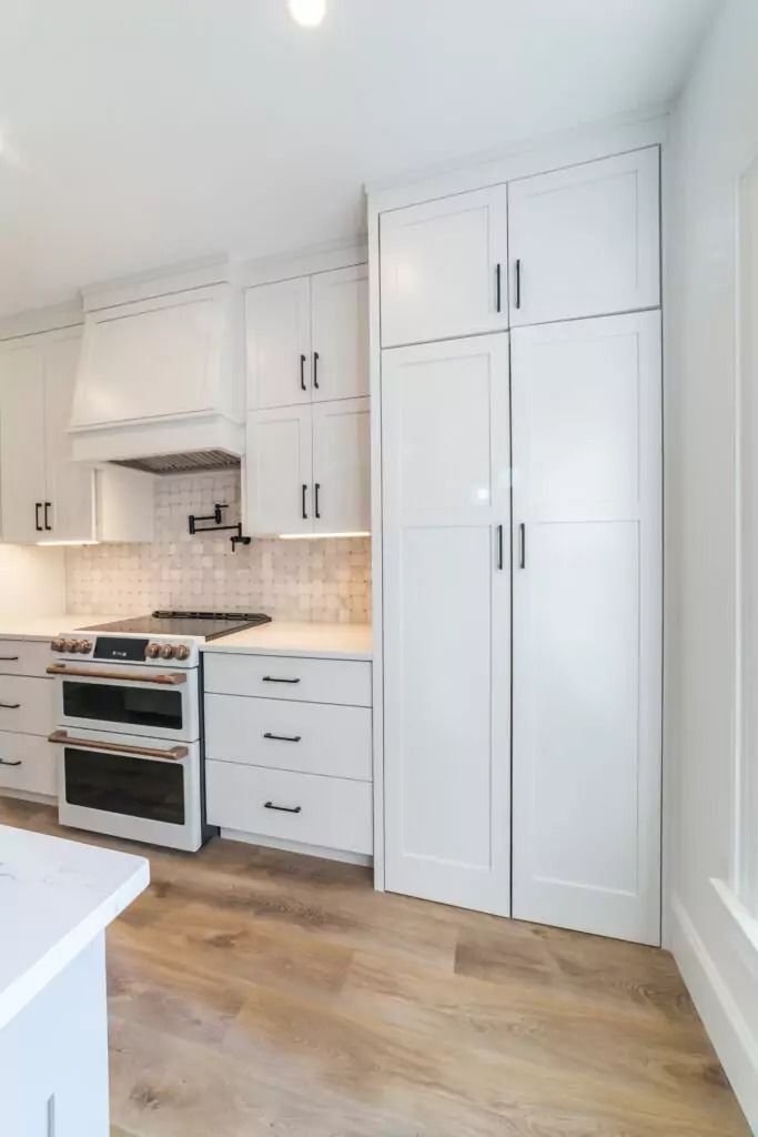 A kitchen with white cabinets , a stove and a refrigerator