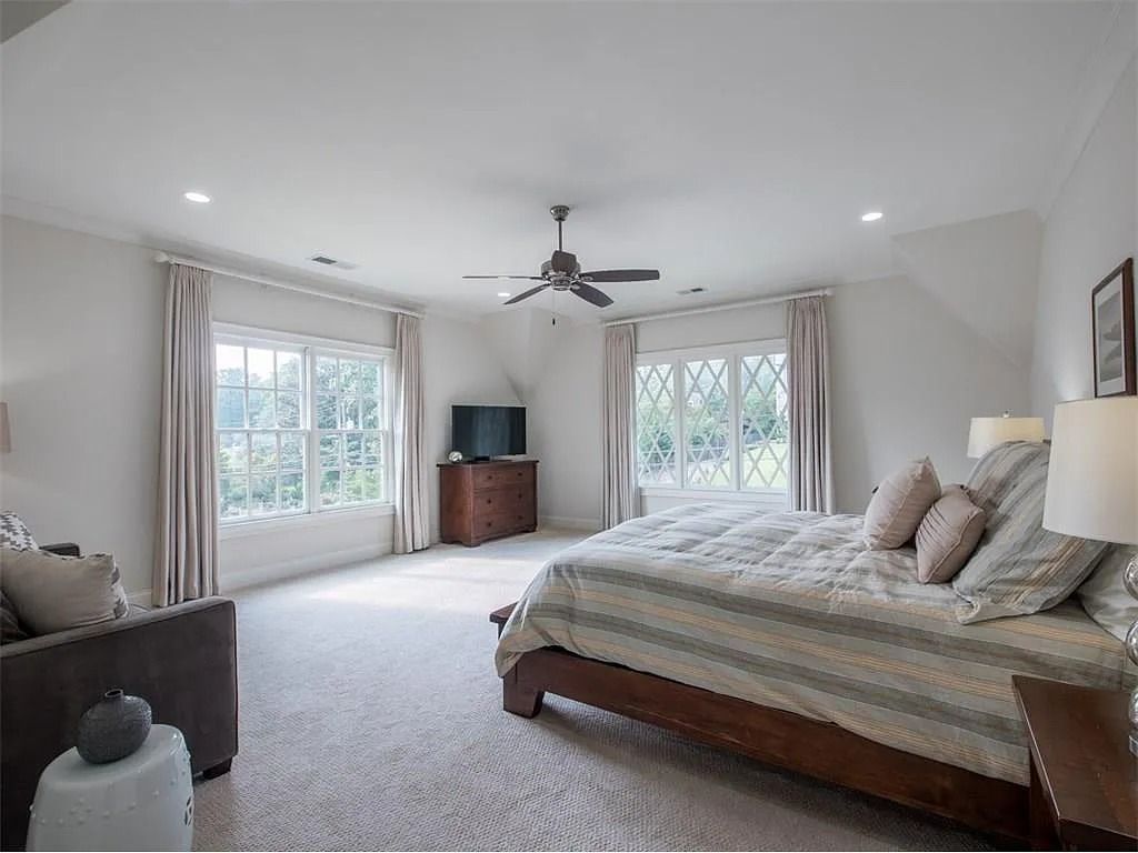 There is a large bed in the middle of the room with a ceiling fan.