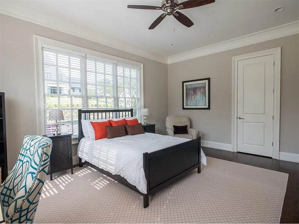 A bedroom with a bed , chair , nightstand and ceiling fan.