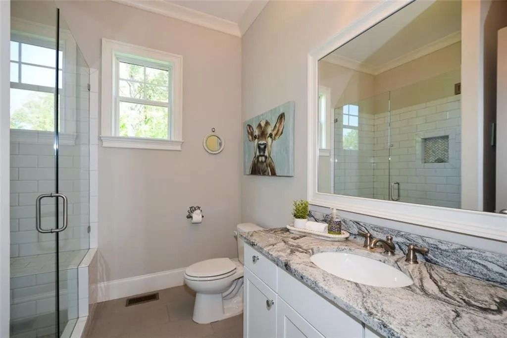 A bathroom with a toilet , sink , mirror and shower.