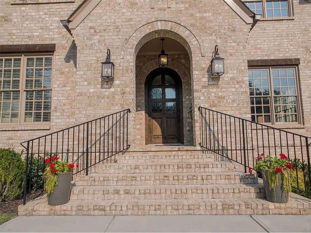 The front door of a brick house with a wrought iron railing and stairs leading up to it.
