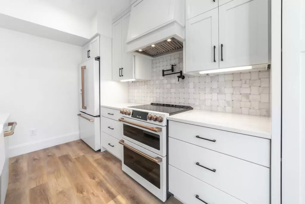 A kitchen with white cabinets , a stove and a refrigerator.