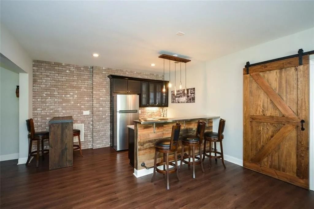 A kitchen with a bar and stools and a sliding barn door.