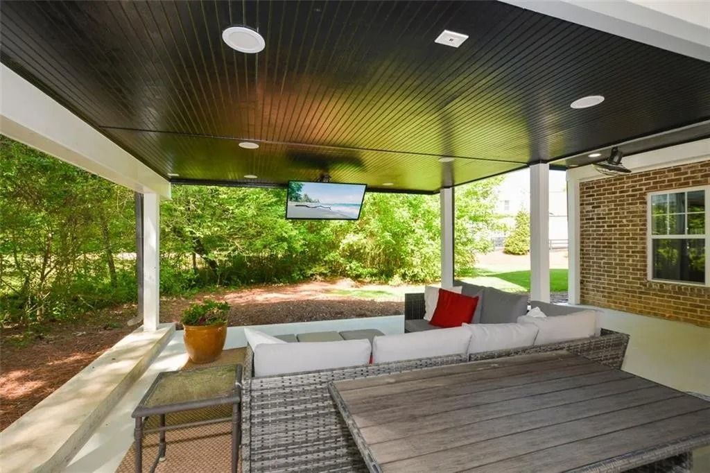 A patio with a couch and a table and a television on the ceiling