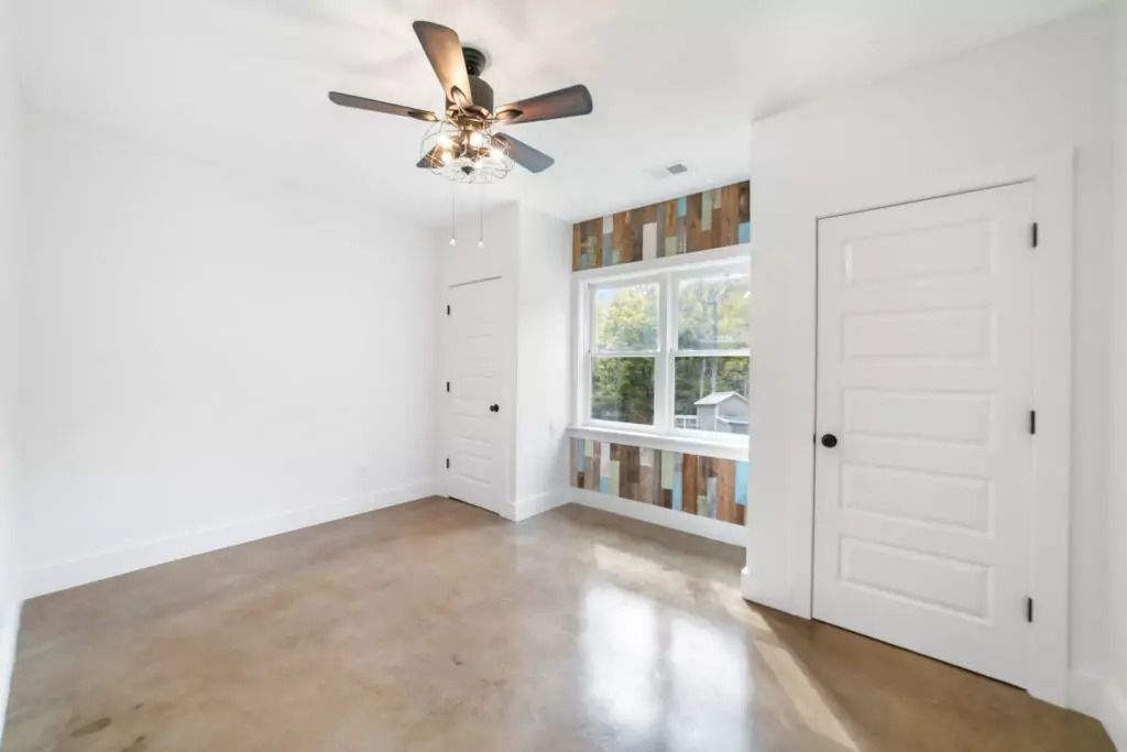 An empty room with a ceiling fan and a large window.