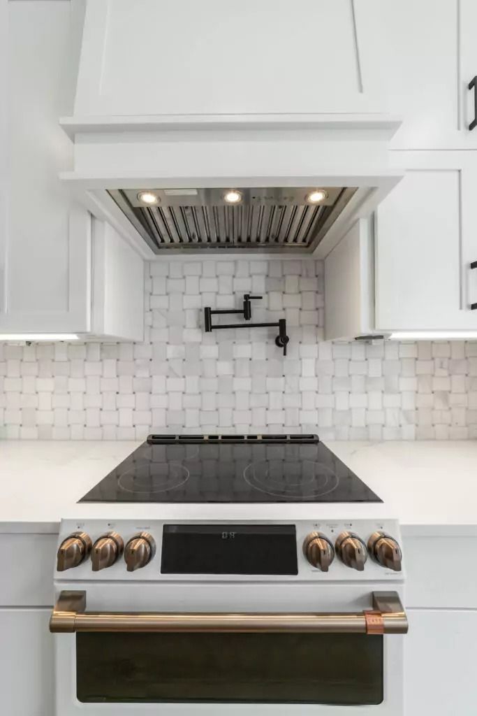 A kitchen with a stove top oven and a hood above it.