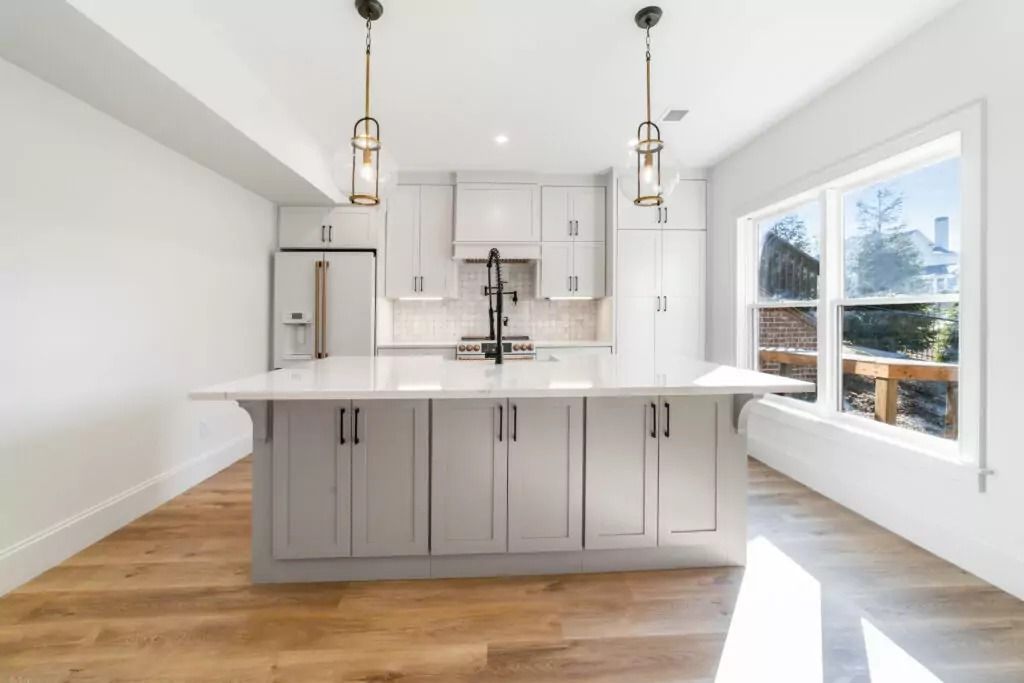 An empty kitchen with white cabinets and a large island.