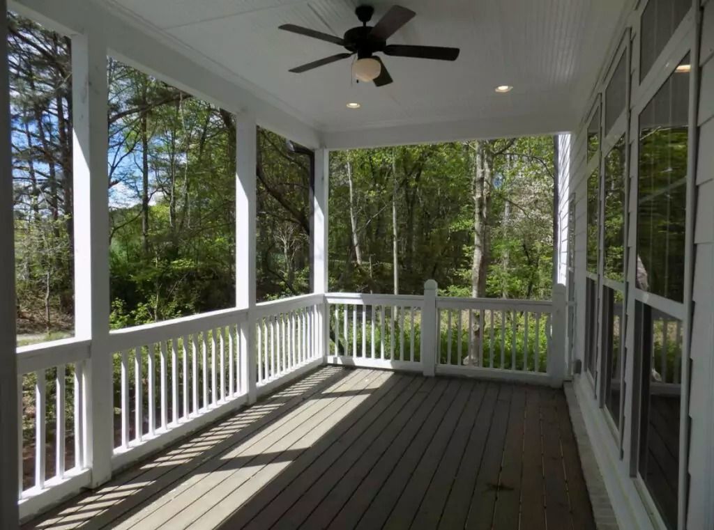 A screened in porch with a ceiling fan and lots of windows