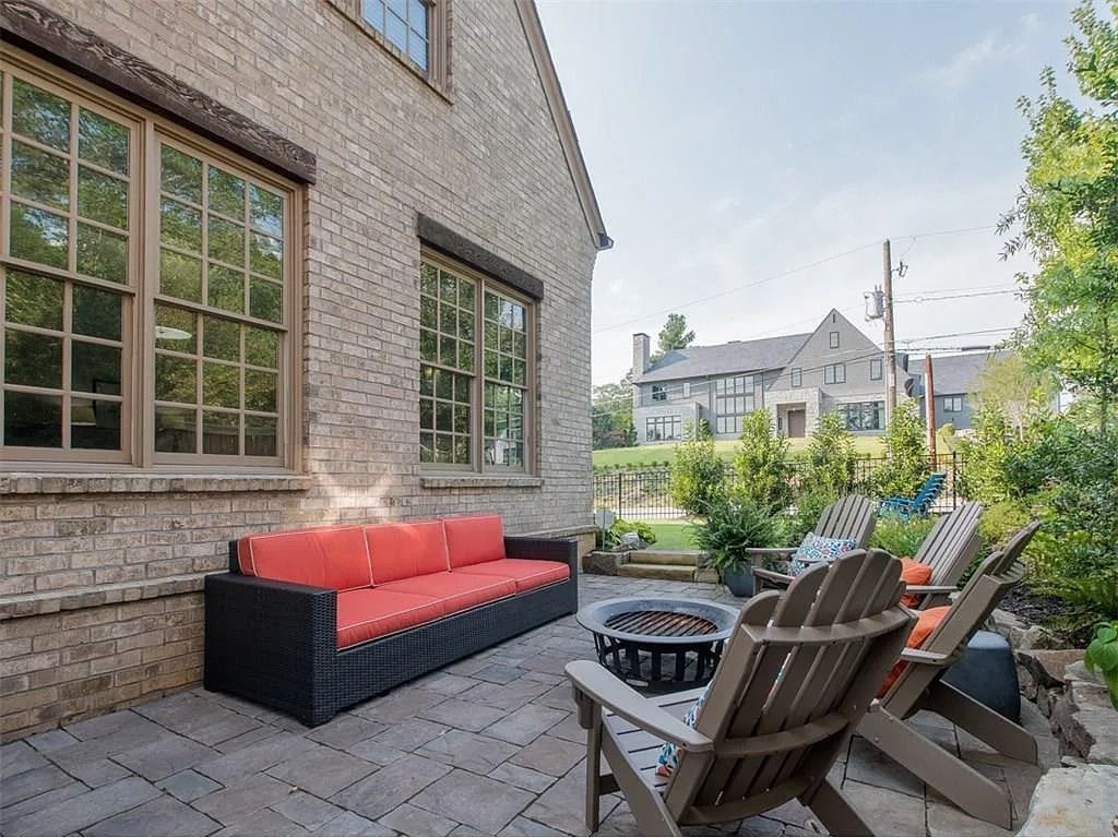 A patio with a couch and chairs and a fire pit.