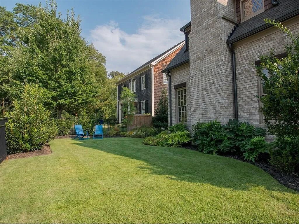 A large brick house with a lush green lawn in front of it.