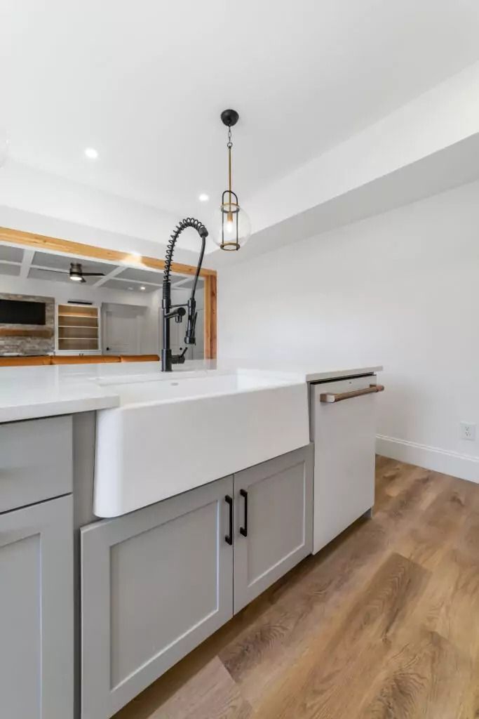 A kitchen with a white farmhouse sink and white cabinets.