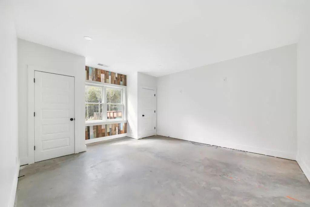 A large empty room with white walls and a concrete floor.