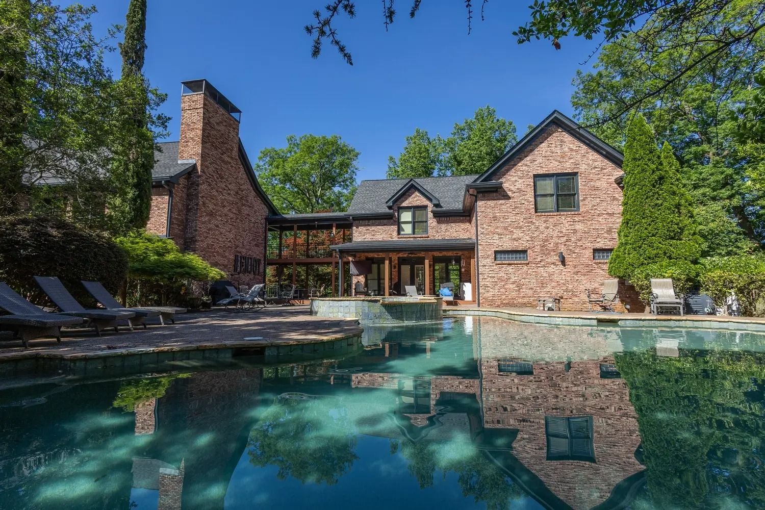A large brick house with a large swimming pool in front of it.