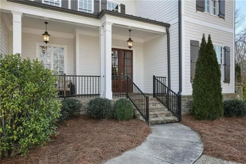 A white house with a porch and stairs leading up to it.