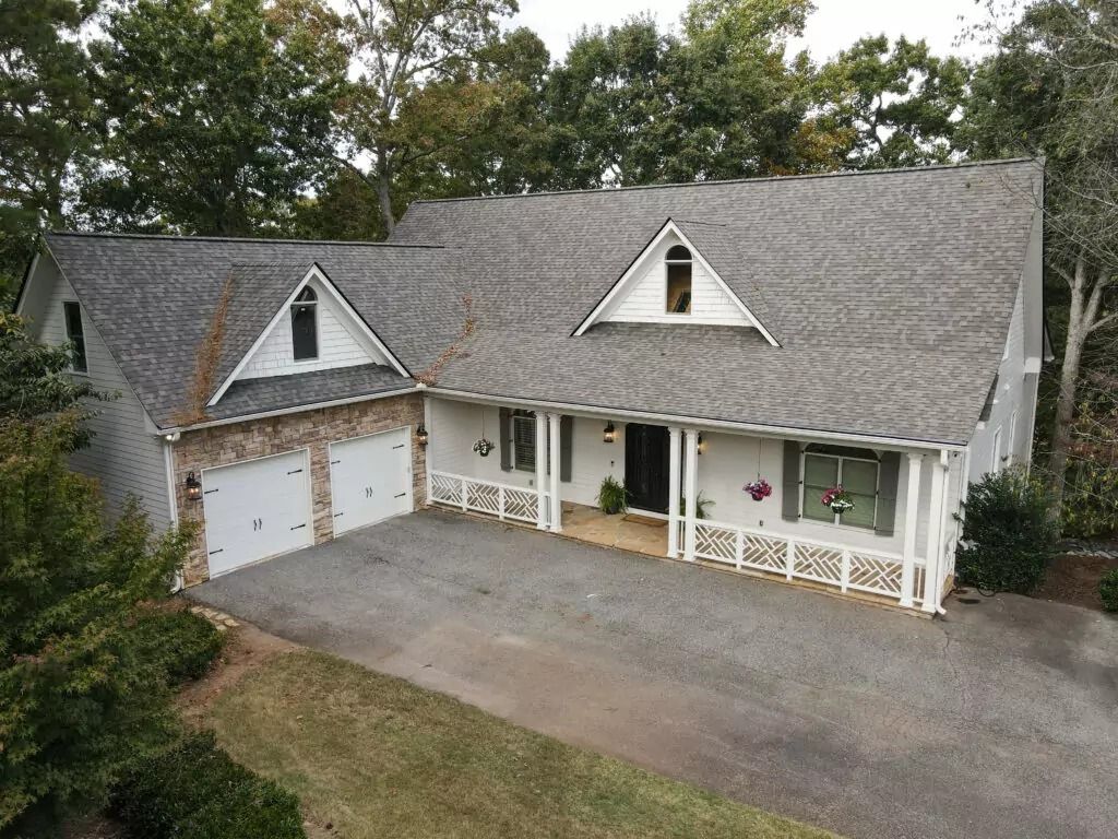 An aerial view of a large white house with a gray roof surrounded by trees.