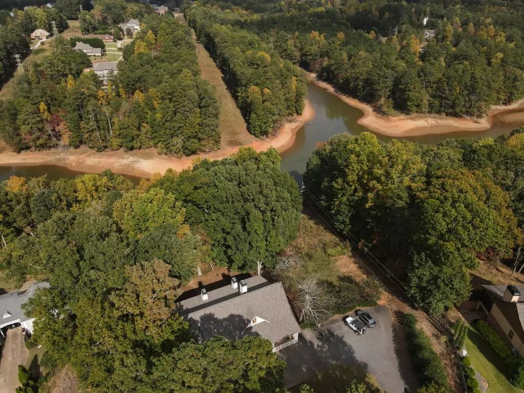 An aerial view of a lake surrounded by trees and houses.