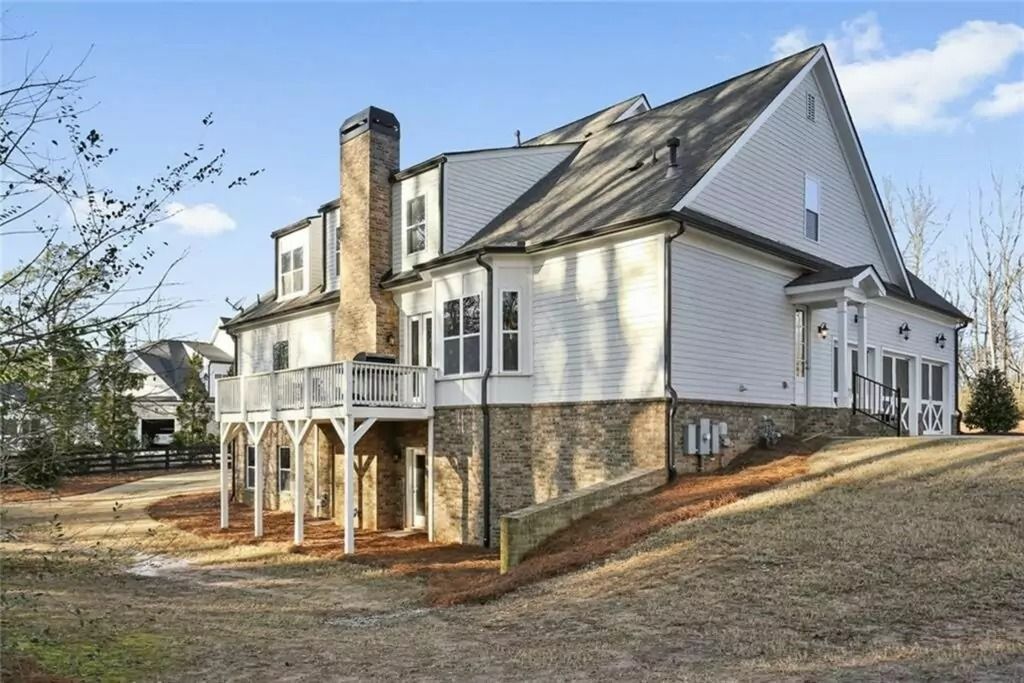 A large white house with a metal roof is sitting on top of a dirt hill.